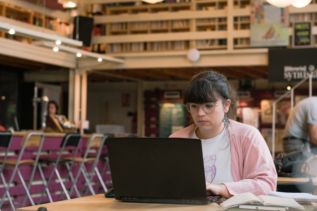 Noia observa la pantalla d'un ordinador en un espai comunitari.