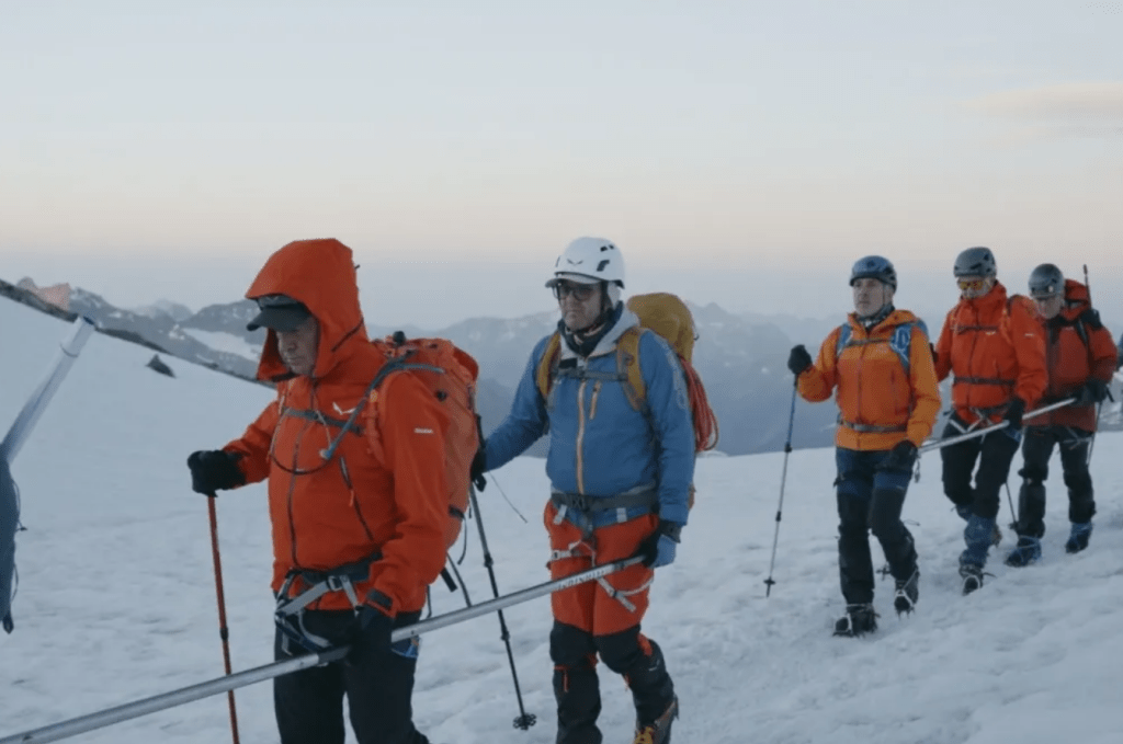 Foto de dos grups de persones, agafant les barres direccionals, vestides d'alpinisme, en una muntanya nevada.