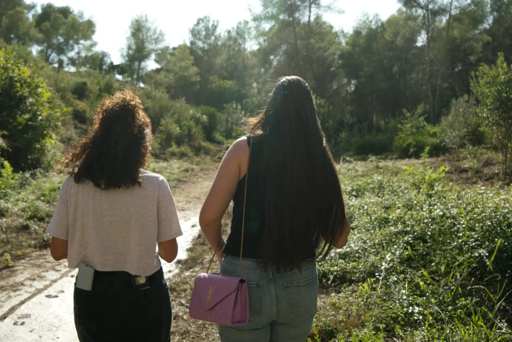 Foto de espaldas de Raquel Heredia y la entrevistadora caminando por el bosque.