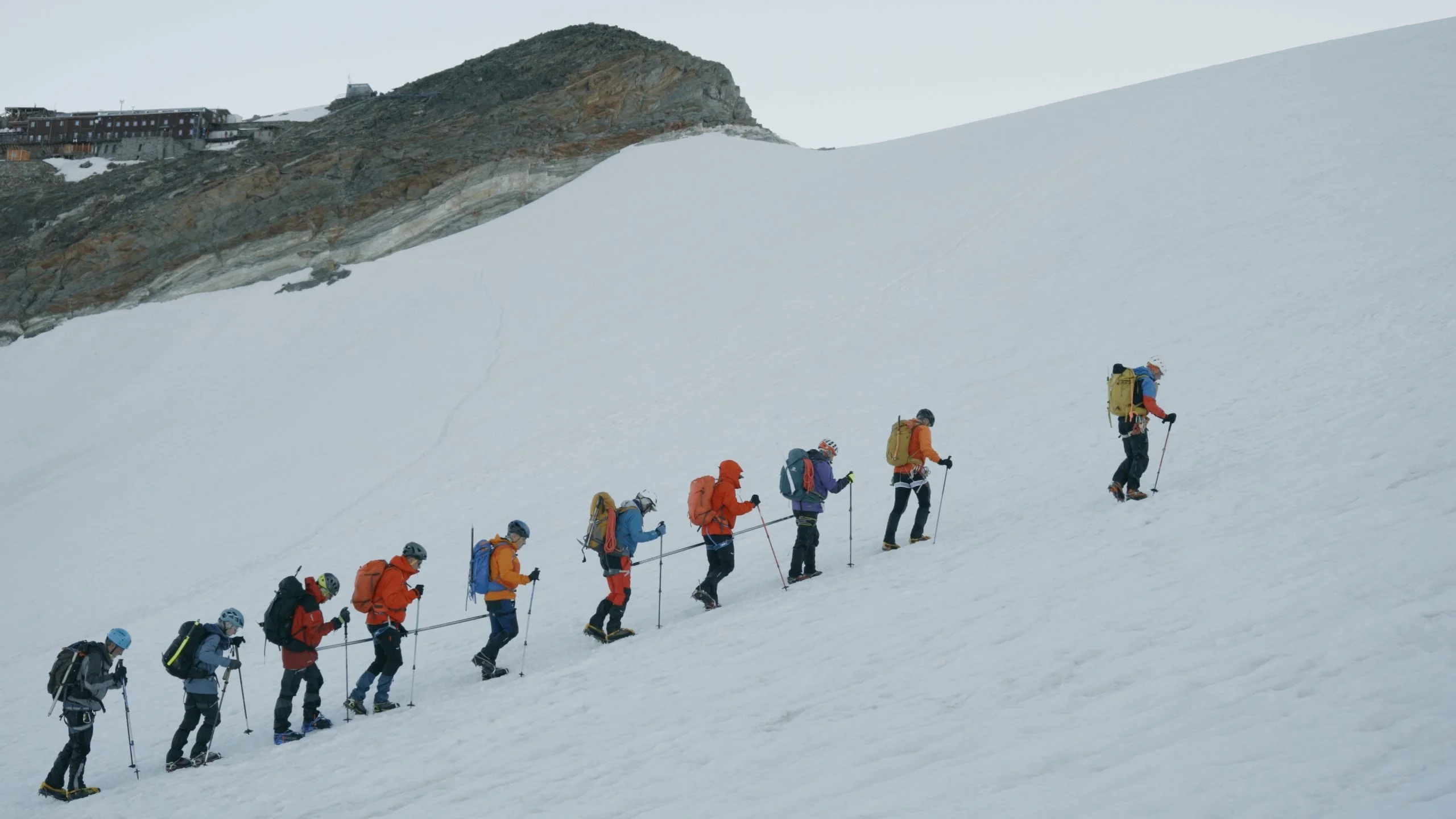 Foto d'un grup de persones equipades amb roba d'alpinisme caminen cordades per la neu.